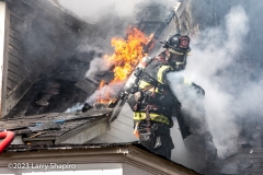 A firefighter exposes hidden fire behind roofing material. Larry Shapiro photo