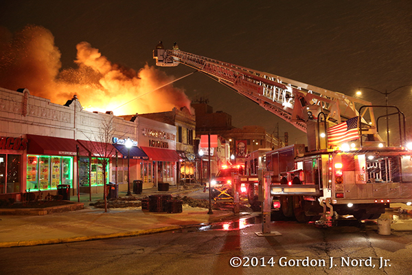 tower ladder working at night fire scene with big flames