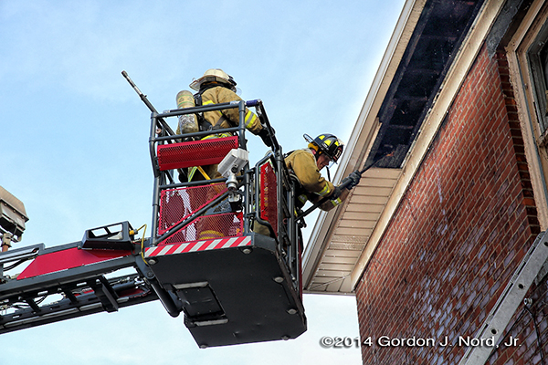 firemen work from tower ladder basket