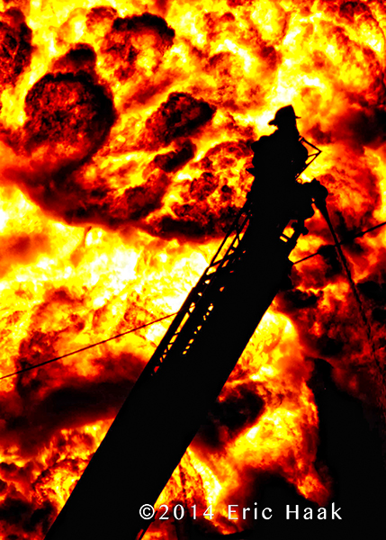 silhouette of fireman on ladder with massive flames