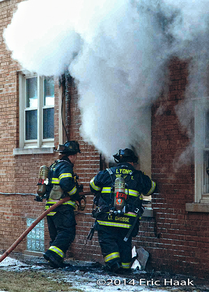 firemen with hose line at apartment building fire