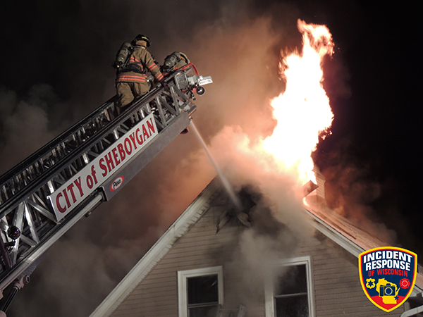firemen battle house fire from aerial ladder