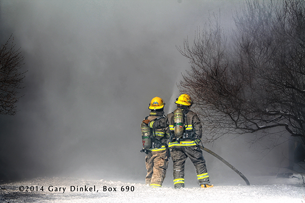 firemen with hose line at winter fire scene with wall of smoke