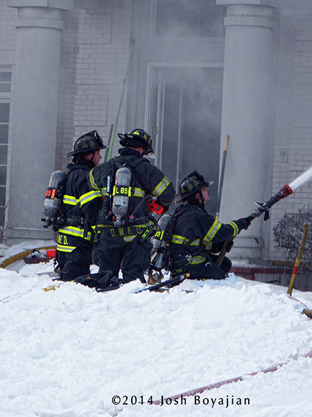 firefighters with hose at winter fire scene