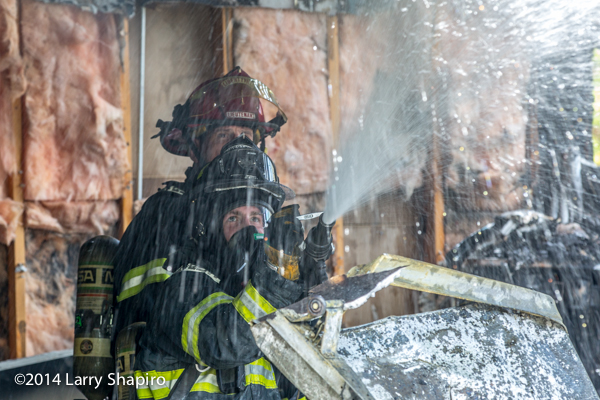 firefighter sprays water with hose