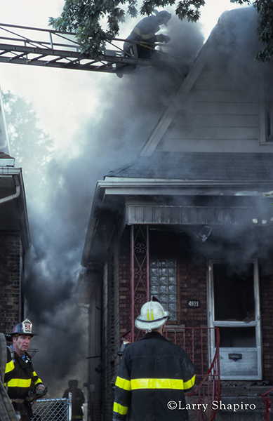firemen battle a house fire with smoke and flames
