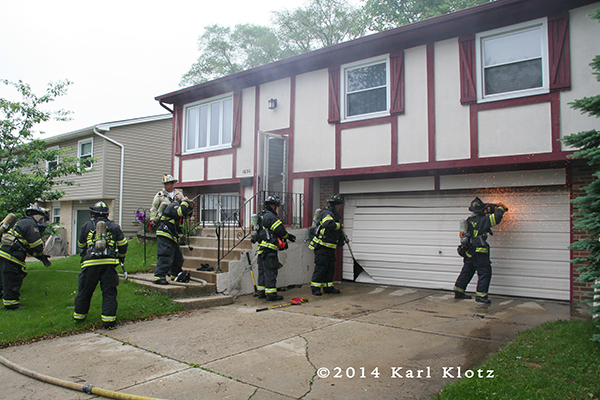firemen cut garage door at house fire