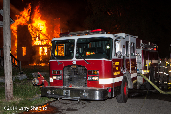 Detroit fire engine with burning structure at night