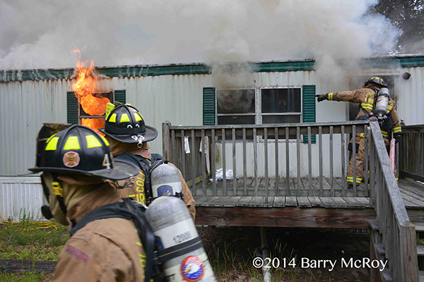 firemen enter a burning mobile home