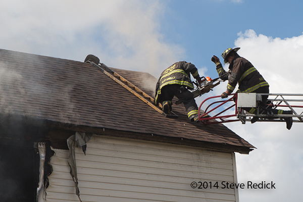 firemen ventilate roof of house