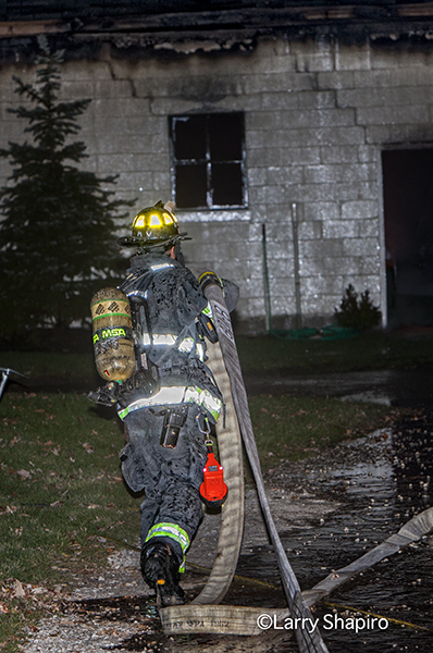 fireman pulling hose at night
