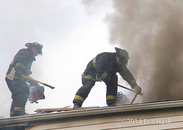 firemen vent roof at house fire
