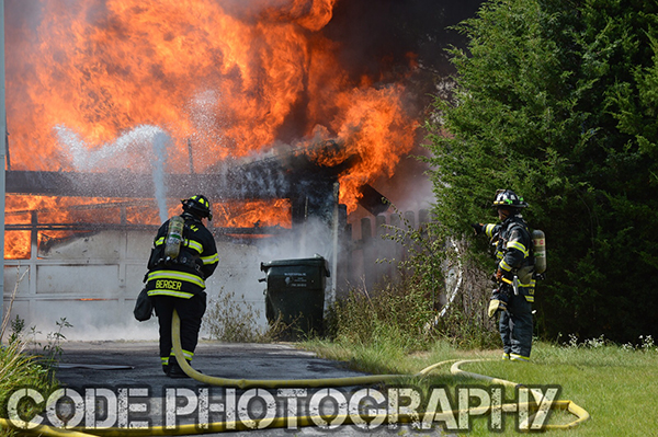 fireman approaches fully involved garage fire