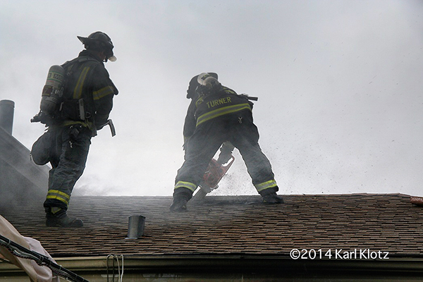 firemen bending roof at house fire