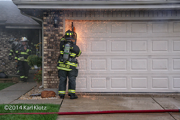 fireman cuts garage door with saw