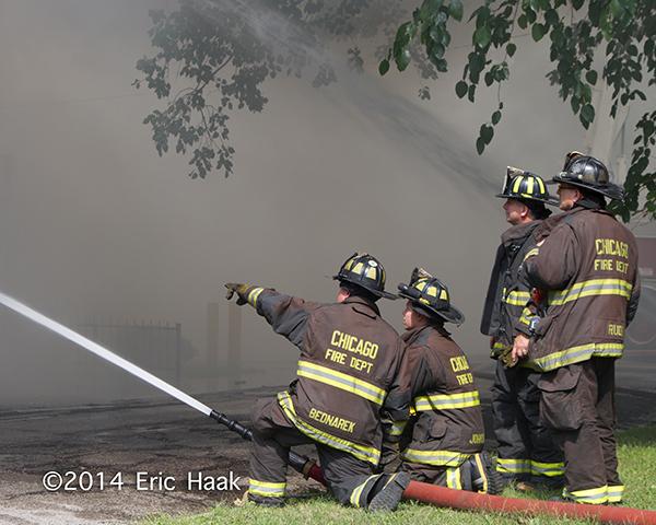 firefighters with hose at smokey fire scene