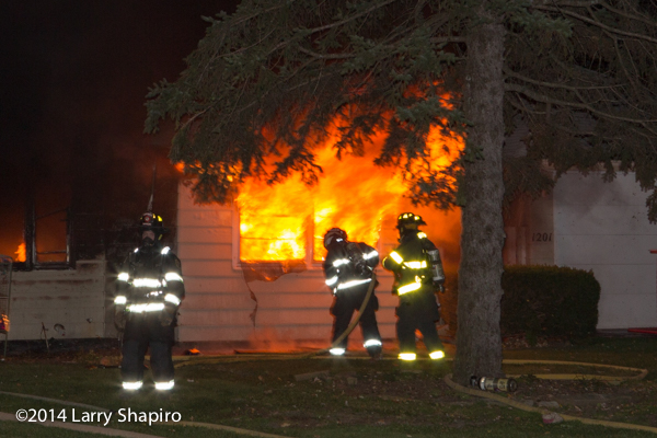firemen with house full engulfed in flames