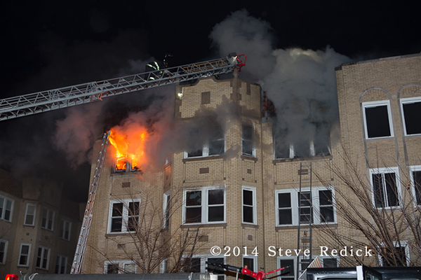 Chicago firefighters on aerial ladder with heavy fire and smoke