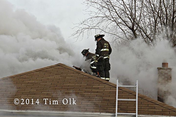 firemen on house roof with smoke