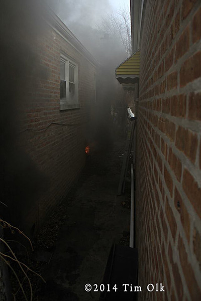 narrow gangway separates house from neighbor's burning house