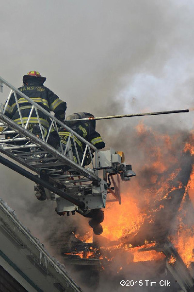 firemen on aerial ladder with heavy smoke and fire