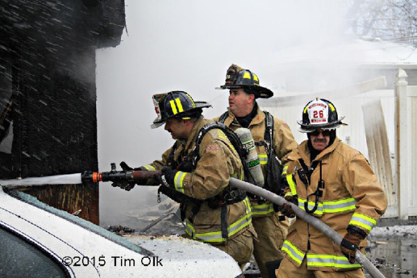 firemen with hose at winter house fire