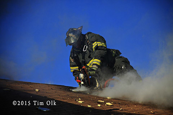 fireman vents roof with saw at house fire