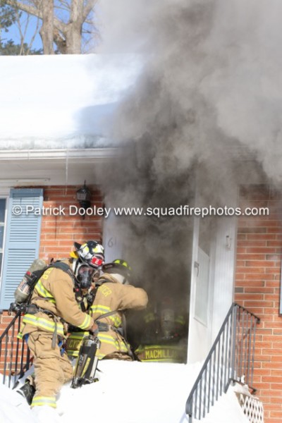 firemen take a line into a house with heavy smoke