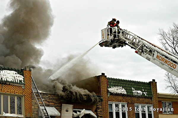 fireman works from tower ladder bucketat fire scene