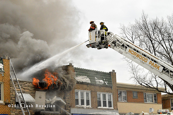 fireman works from tower ladder bucketat fire scene