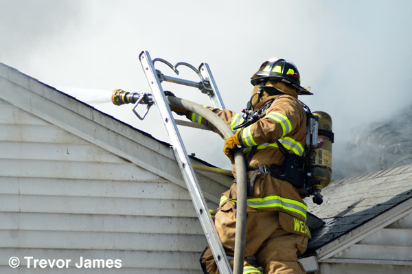fireman at house fire on ladder with hose
