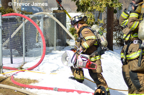 fireman carries saw through snow at house fire