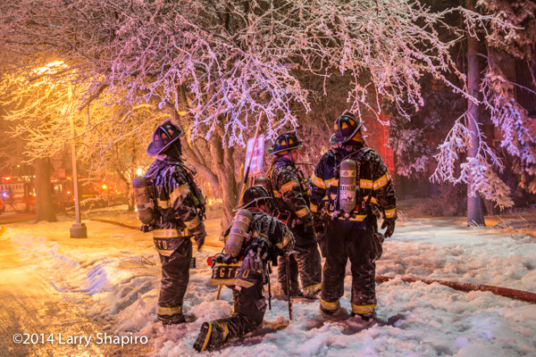 firemen and trees covered with ice at winter fire scene