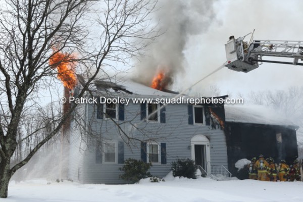 flames through the roof of a two-story house