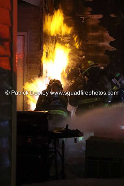 firemen fight flames at a house at night