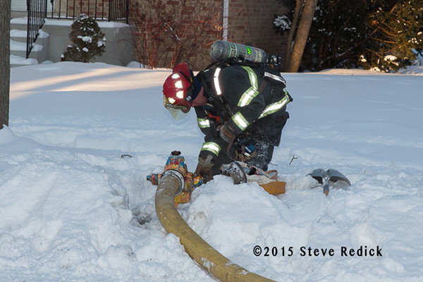 fireman connects hose to hydrant buried by snow