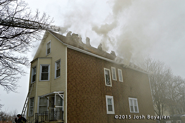 firemen on roof vent house with smoke