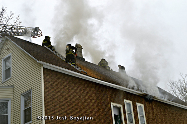firemen on roof vent house with smoke