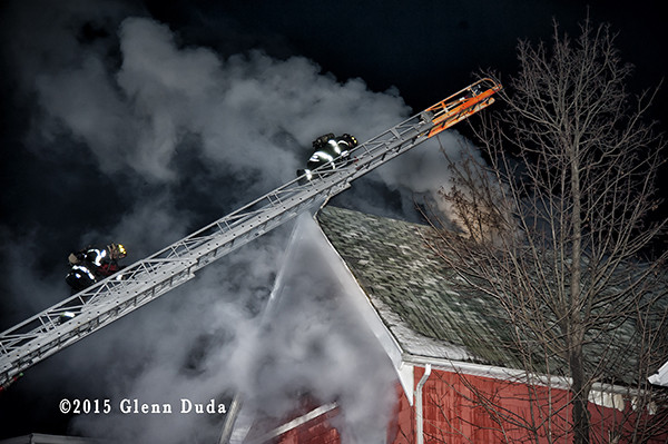 fireman climbs Seagrave aerial ladder at night fire scene
