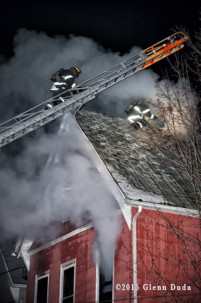 fireman climbs Seagrave aerial ladder at night fire scene
