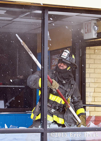 fireman breaks windows at commercial fire scene