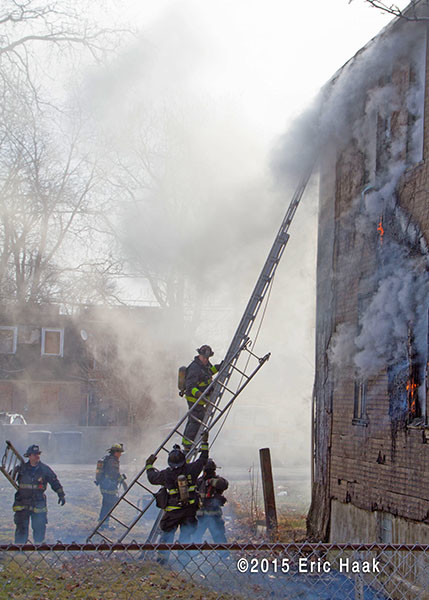 firemen climb ladder at smokey fire scene