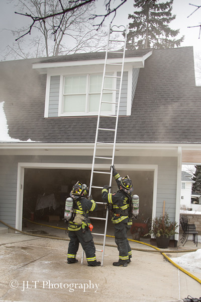 firemen raise a ground ladder at a house fire 