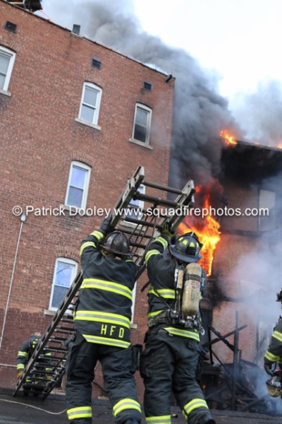 firemen raise ladder at building fire
