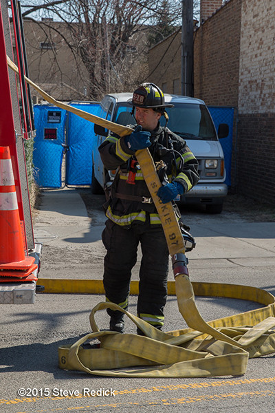 fireman pulls hose from fire engine