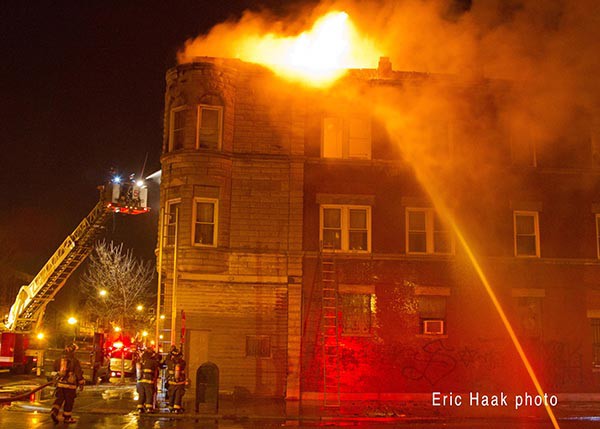 flames through roof of apartment building fire at night