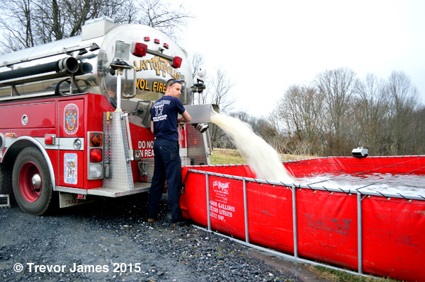 fire department water tender dumping water into a portable tank