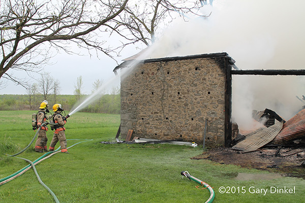 fireman with hose after fire destroyed a barn
