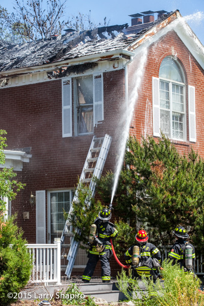firemen apply foam at a house fire