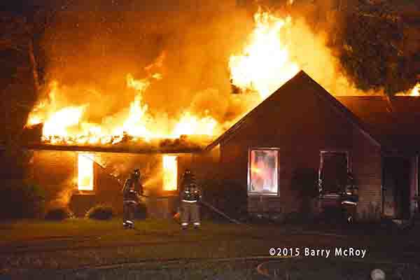 firemen battle a rural house engulfed in fire